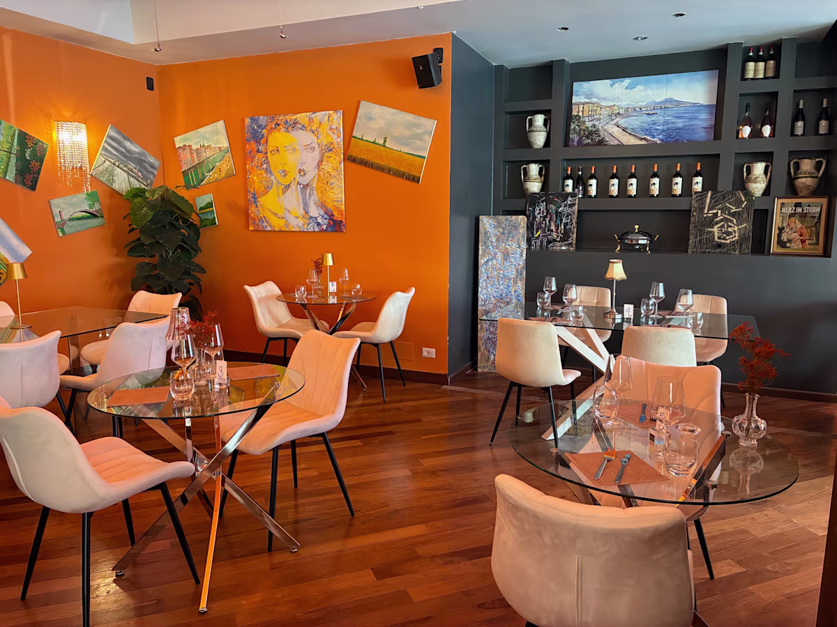 Sala elegante Dal Professore con parete arancio, tavoli apparecchiati e luci calde