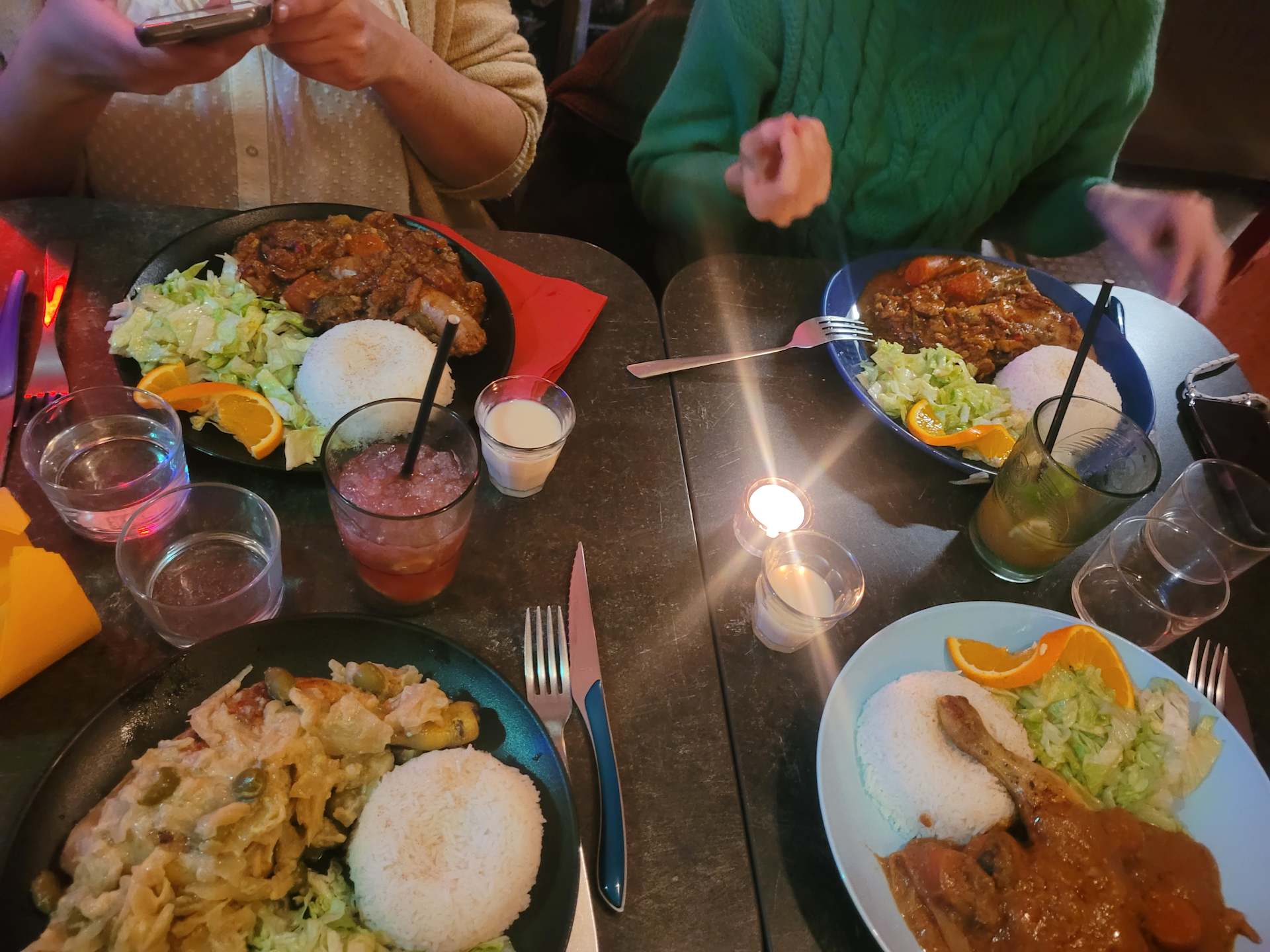 Sc&egrave;ne de repas anim&eacute;e avec des plats vari&eacute;s : p&acirc;tes cr&eacute;meuses aux l&eacute;gumes et fruits de mer, accompagn&eacute;es de riz, et poulet brais&eacute; dans une sauce &eacute;pic&eacute;e, servi avec une salade fra&icirc;che.