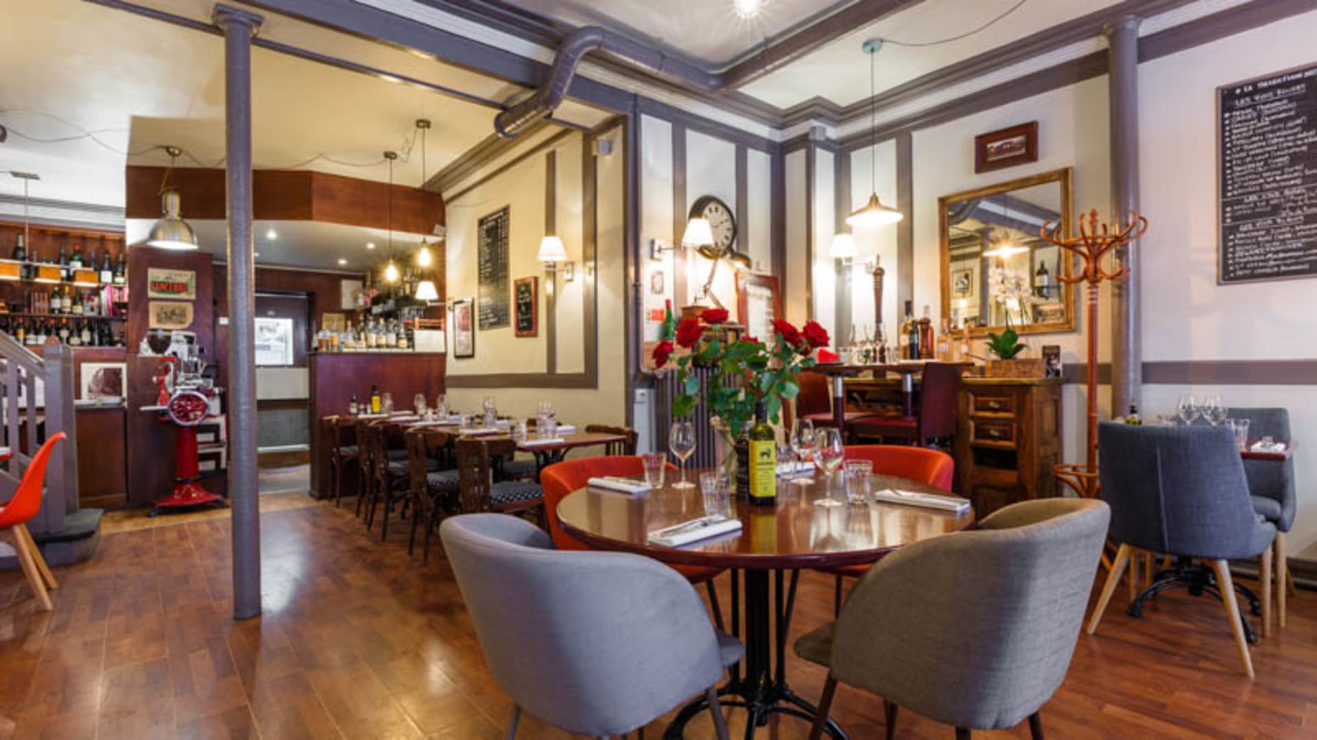 Int&eacute;rieur chaleureux avec un m&eacute;lange de tables rondes et de chaises confortables, murs d&eacute;cor&eacute;s de photos encadr&eacute;es et d'un menu au tableau, cr&eacute;ant une ambiance accueillante.