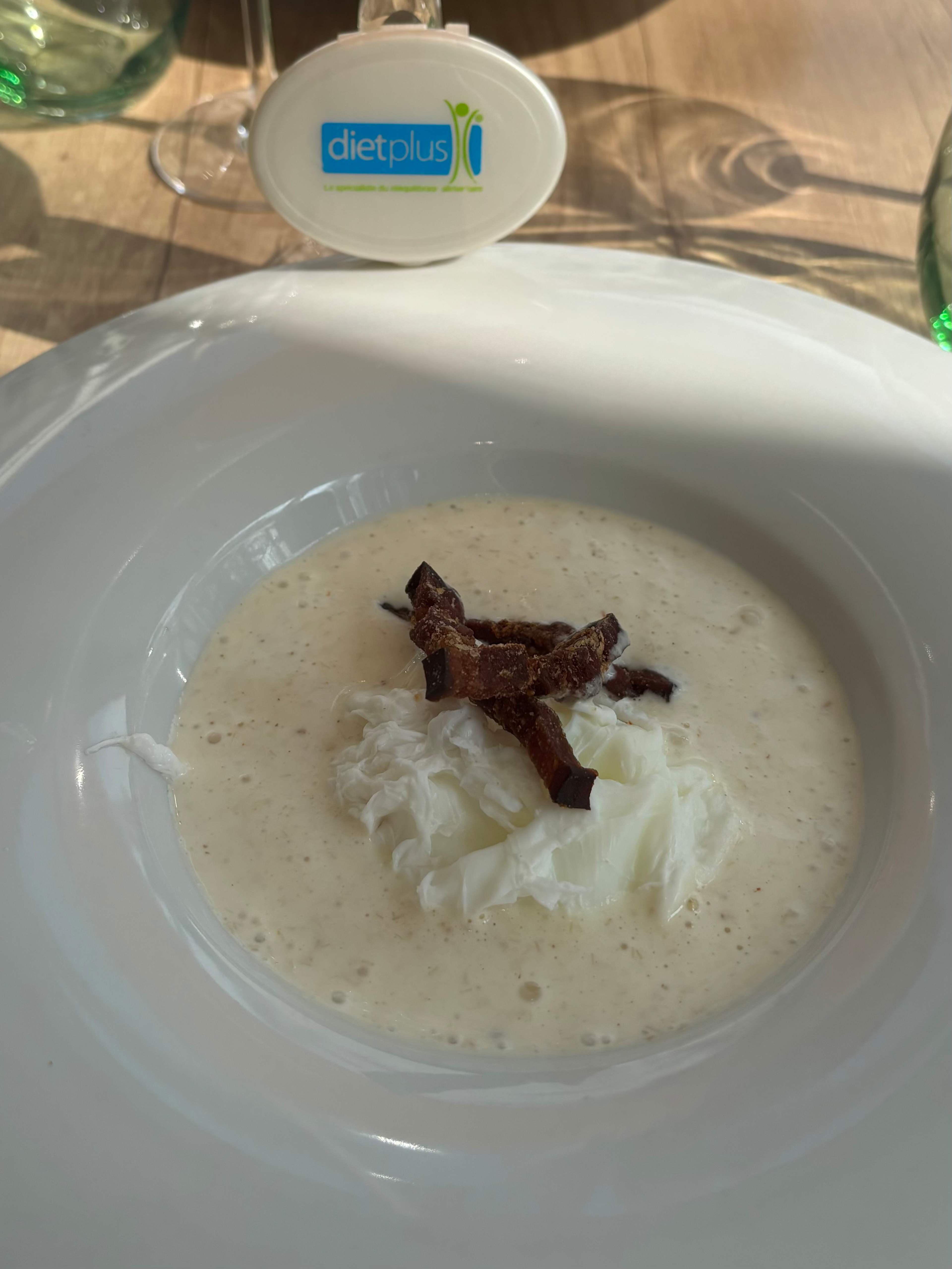 Soupe crémeuse avec des morceaux délicats d'œuf poché et des champignons fins, offrant une présentation élégante et raffinée.
