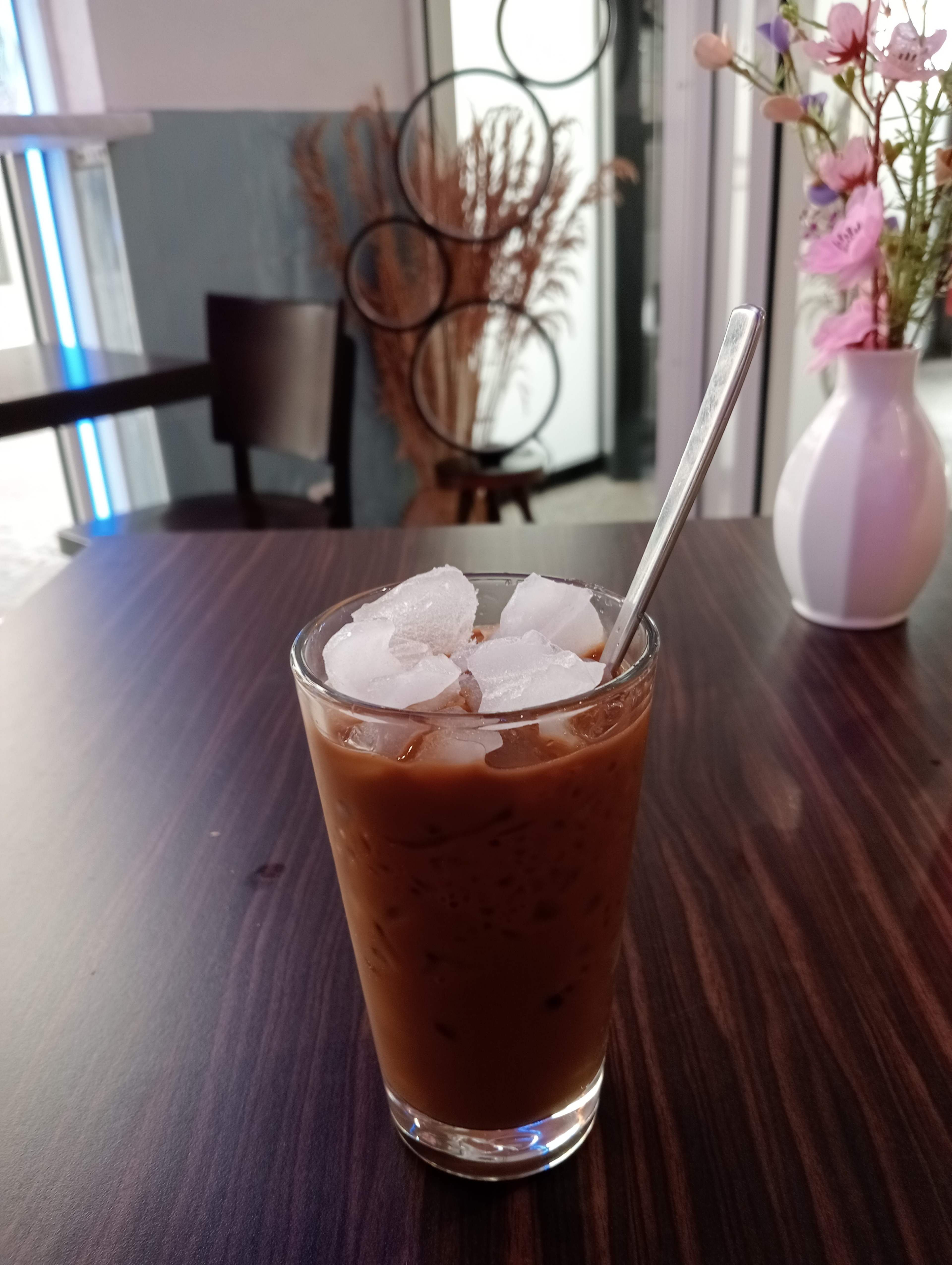 Boisson glacée au café, de couleur brun foncé, avec une texture crémeuse, servie dans un verre transparent rempli de glaçons.