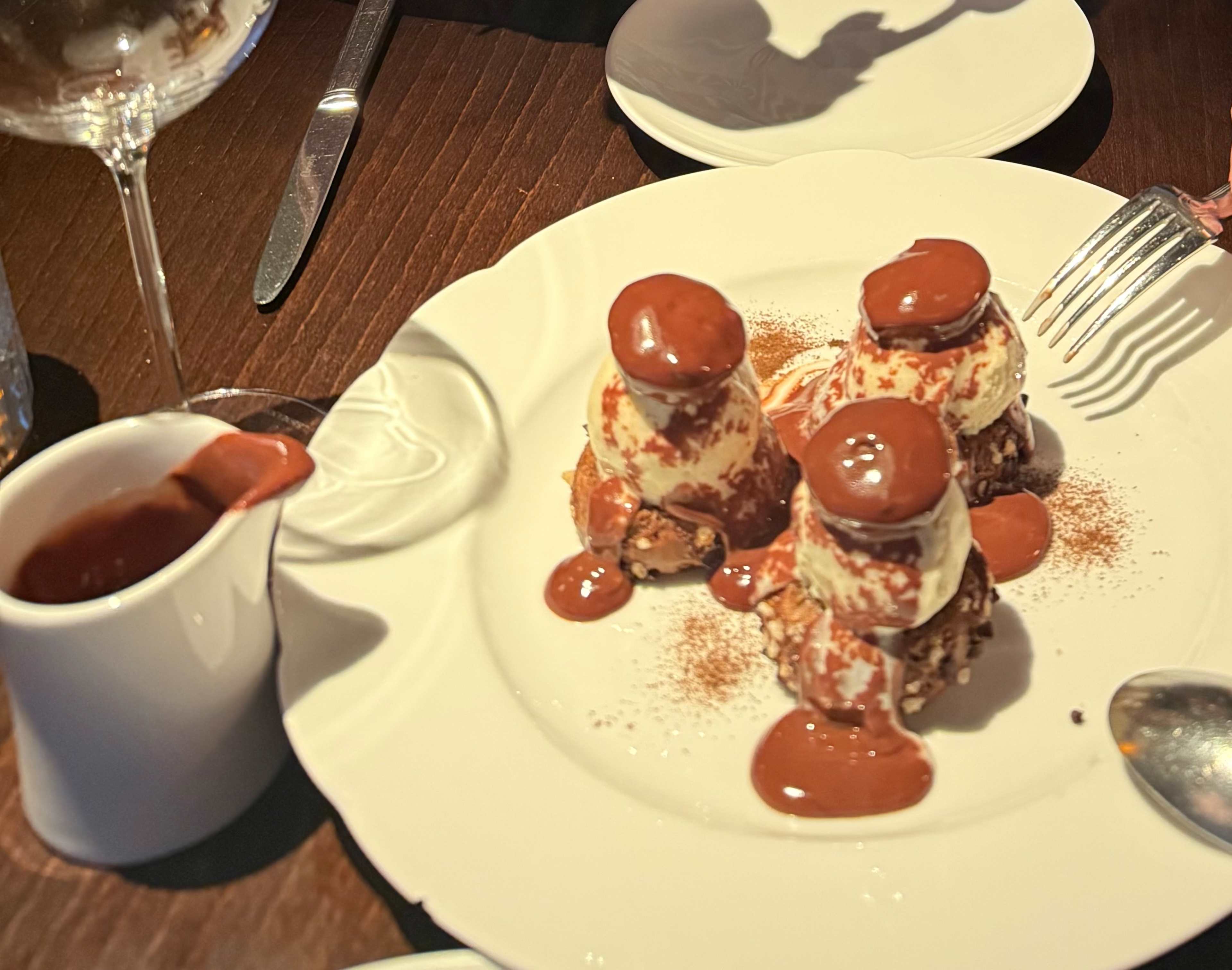 Dessert délicieux avec trois boules de crème glacée à la vanille, nappées d'une épaisse sauce au chocolat et saupoudrées de cacao.