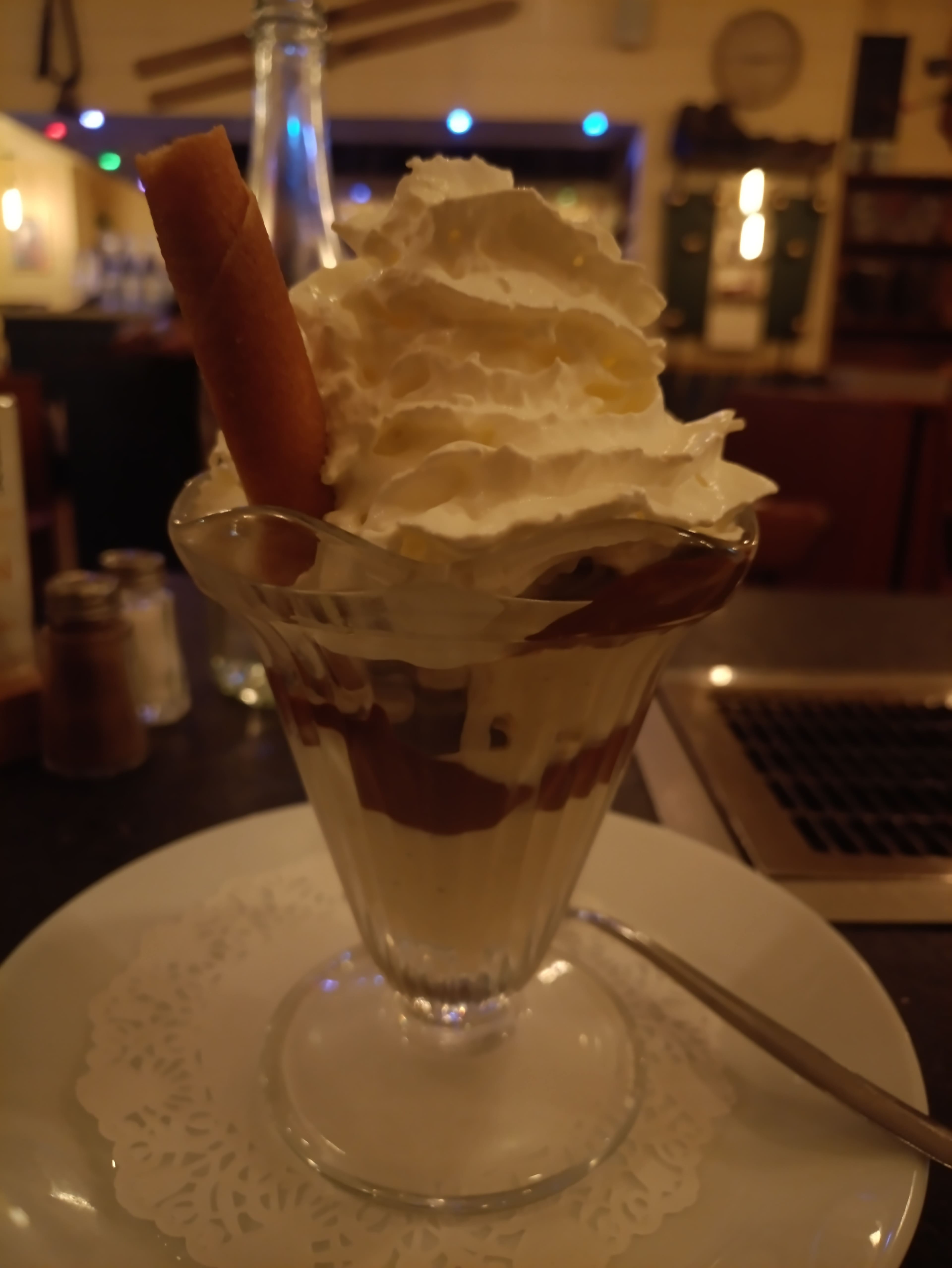 Dessert en couches avec une généreuse couche de crème fouettée, un mélange épais au chocolat ou au café en dessous, et un bâtonnet de gaufrette croustillant.