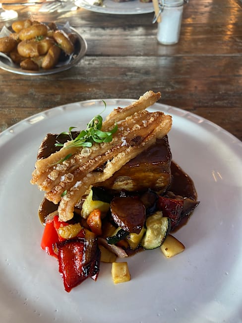 Carne de cerdo estofada con salsa oscura, acompañada de verduras salteadas y cebollín picado.