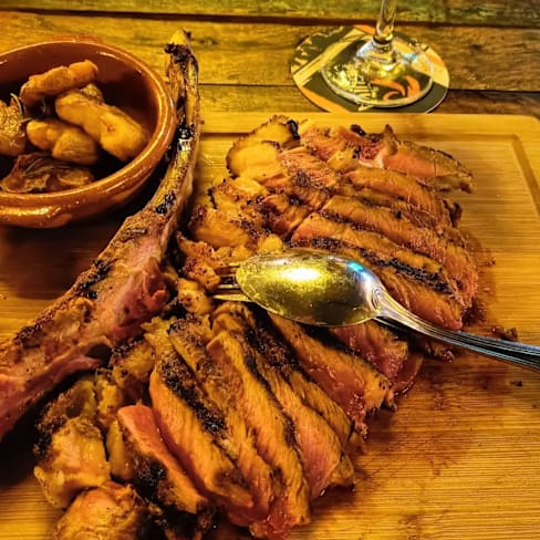 Costillas de cordero a la parrilla, tiernas y jugosas, acompañadas de verduras asadas como batatas y zanahorias.