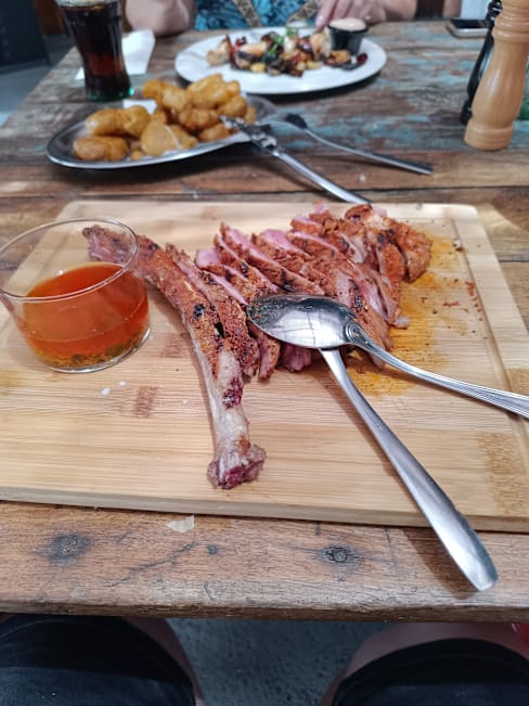 Rodajas de carne de cerdo jugosa y crujiente, acompañadas de una salsa ámbar y frituras doradas.