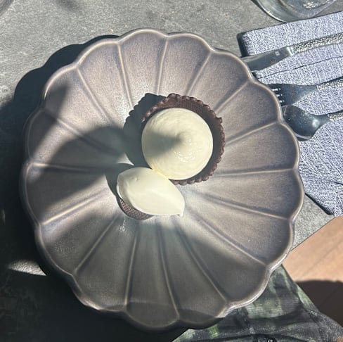 Dessert délicat avec une mousse crémeuse au chocolat dans une coque en chocolat, accompagné d'une boule de sorbet léger, offrant un contraste rafraîchissant.