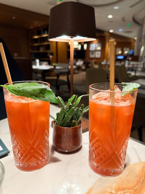 Deux cocktails rafraîchissants servis dans de grands verres texturés, garnis d'un brin de basilic frais.