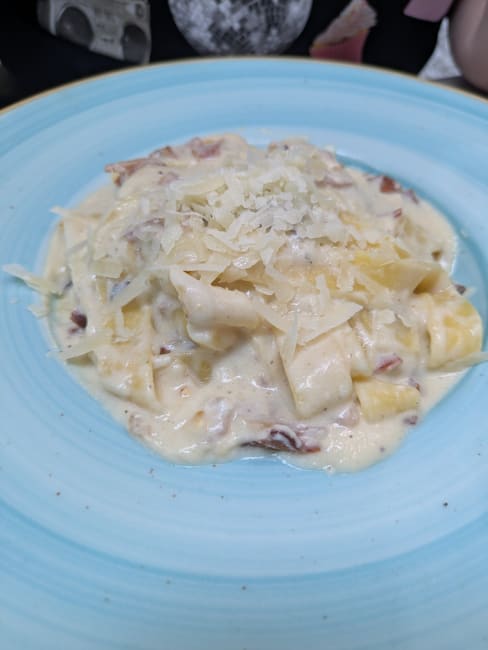 Pasta fettuccine cremosa con salsa de queso parmesano y pancetta crujiente.