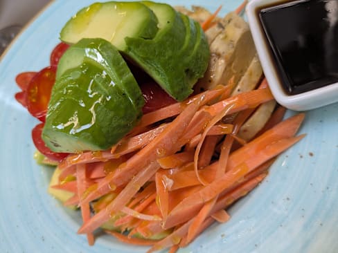 Ensalada fresca con pepino crujiente, tomates cherry y zanahorias ralladas, aderezada con salsa.