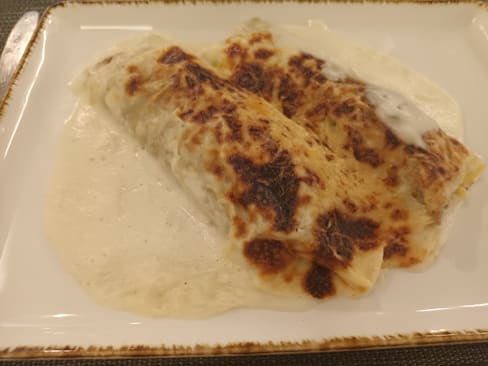 Pasta rellena en salsa blanca cremosa, cubierta con una capa dorada y asada.