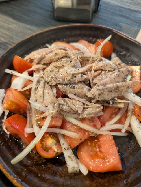 Ensalada fresca con pollo desmenuzado, tomates rojos y cebollas, sazonada con pimienta negra.