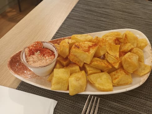 Papas fritas crujientes con pimentón, acompañadas de un dip cremoso y semillas de sésamo.