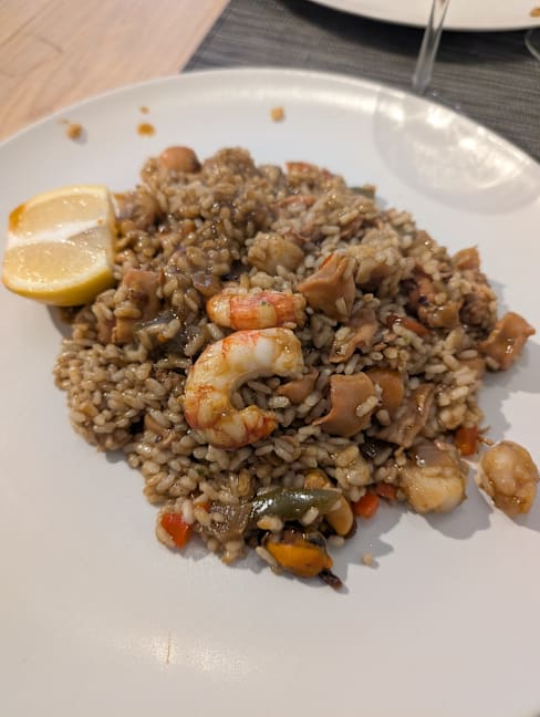 Risotto de mariscos con camarones y pollo, cocido en una base cremosa y acompañado de verduras coloridas y un gajo de limón.