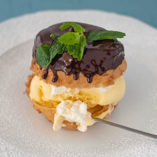 Sobremesa decadente com massa em camadas recheada com gelado de baunilha, coberta com um glacê de chocolate brilhante e guarnecida com folhas de hortelã fresca.