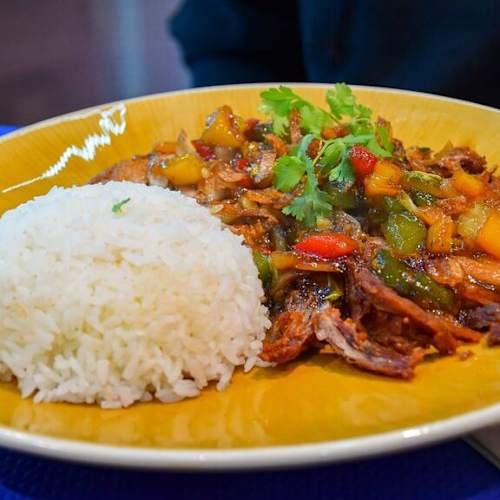 Plat généreux de viande effilochée tendre dans une sauce savoureuse, accompagné de riz blanc moelleux et de légumes colorés, rehaussé d'herbes fraîches.