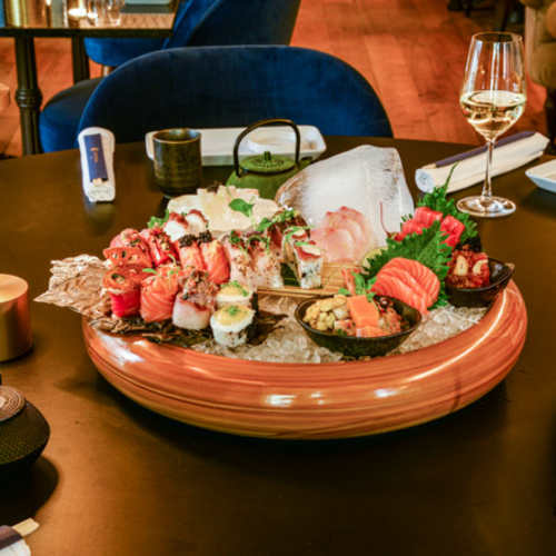 Prato elegante de sushi com sashimi fresco, nigiri com frutos do mar e rolls recheados com abacate, pepino e caranguejo, guarnecido com wasabi e gengibre em conserva.