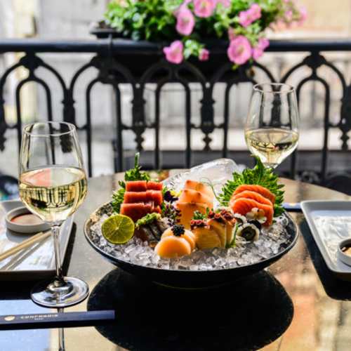 Prato elegante de sushi e sashimi com salmão, atum e peixe-gato, guarnecido com limão e ervas frescas.