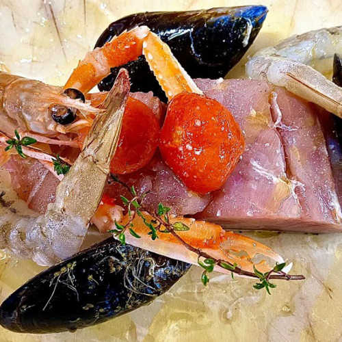 Composizione di frutti di mare con tonno rosa, gamberi, cozze, pomodorini e timo fresco.
