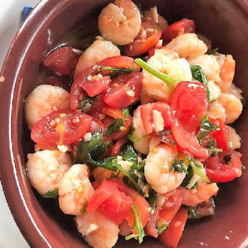 Gamberi succulenti con pomodori a cubetti e erbe fresche, presentati in un piatto leggermente condito.