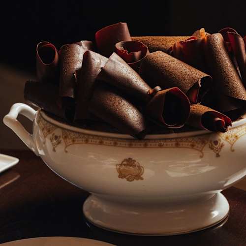 Bol décoratif rempli de copeaux de chocolat noir, présentant une finition brillante et une texture élégante.