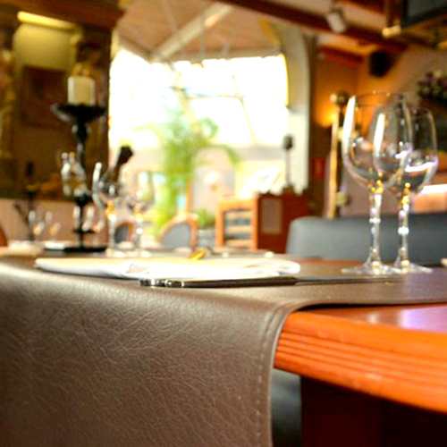 Het interieur van het restaurant heeft een warme en uitnodigende sfeer met elegante glazen, houten tafels en comfortabele zitplaatsen. Zachte verlichting en decoratieve elementen zorgen voor een verfijnde ambiance.