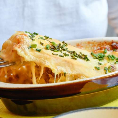 Plat de pâtes au fromage cuit au four, avec des couches de lasagne, une sauce à la viande savoureuse et des herbes fraîches.