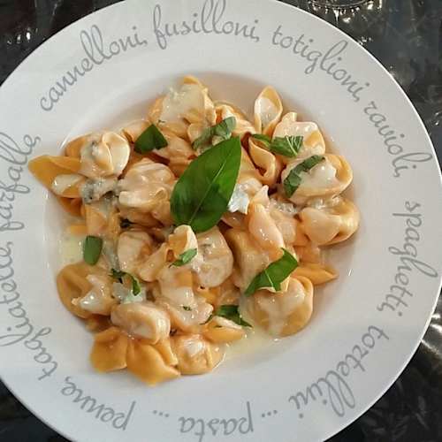 Plat généreux de tortellini enrobés d'une sauce crémeuse, agrémentés de feuilles de basilic frais.