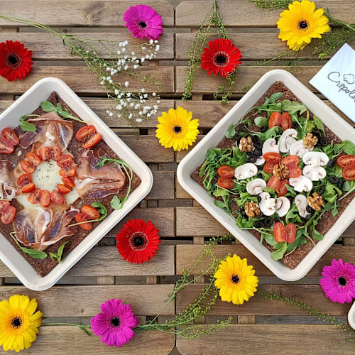 Assortiment color&eacute; de salades avec des l&eacute;gumes frais, prosciutto, fraises et tomates cerises, accompagn&eacute; d'un g&acirc;teau au citron en arri&egrave;re-plan.