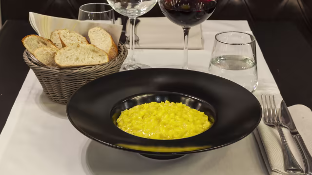 Risotto cremoso al saffron con erbe fresche, accompagnato da pane a fette.