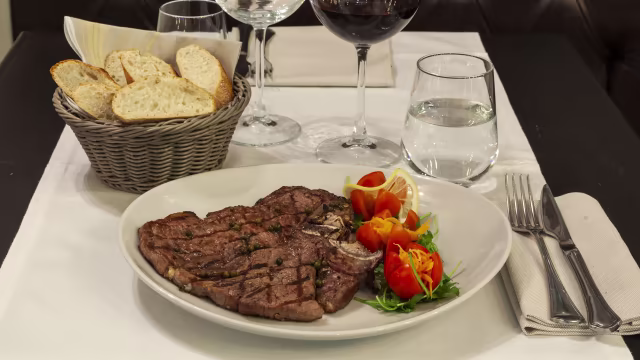 Bistecca grigliata a cottura media, servita con pomodorini, carote grattugiate e limone.