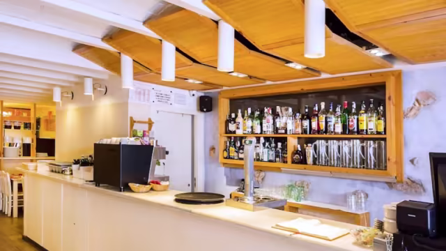 Interior de restaurante moderno con un bar minimalista, estantería bien surtida y ambiente acogedor.