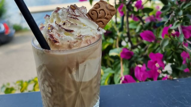 Cremiger Eiskaffee mit Schlagsahne, Schokoladensauce und einem dekorativen Keks, ideal für warmes Wetter.