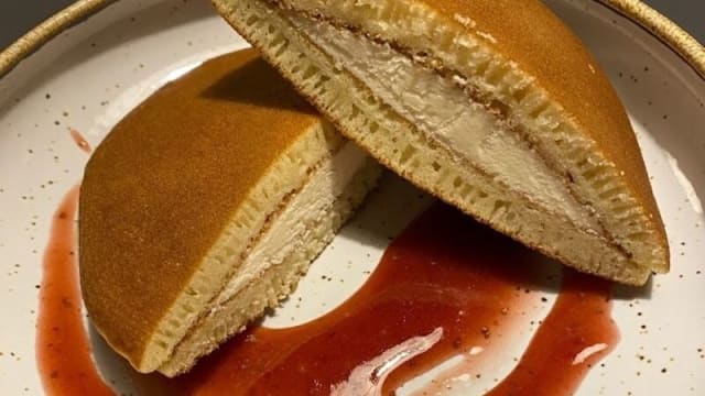 Pancakes esponjosos rellenos de helado de vainilla, acompañados de una salsa roja de frutas que aporta un contraste dulce y ácido.