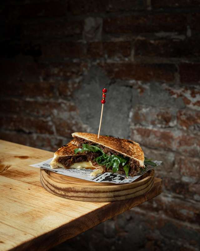 BIKINI BBQ Nuestro sabroso sándwich de carrillera de cerdo, cocinada a baja temperatura y aderezada con aji panca, soja y tamarindo durante 14 hras para lograr una textura jugosa y tierna con queso fundido buscamos un equilibrio perfecto entre dulzura y umami.