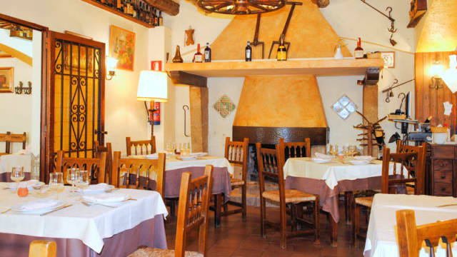 Interior acogedor con muebles de madera, decoración rústica y una chimenea como punto focal, ideal para disfrutar de comidas abundantes.