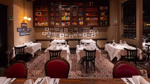 Interno di un ristorante accogliente con tavoli ben disposti, tovaglie bianche e decorazioni nostalgiche, che creano un'atmosfera intima.