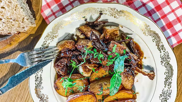 Plat copieux de morceaux de viande tendre, probablement braisée, accompagné de pommes de terre rôties dorées et garnies d'herbes fraîches.