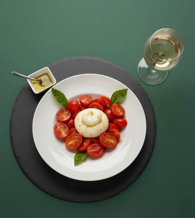 Burrata cremosa com tomate cereja, rúcula e temperos. Uma combinação fresca e deliciosa para os amantes de sabores autênticos.