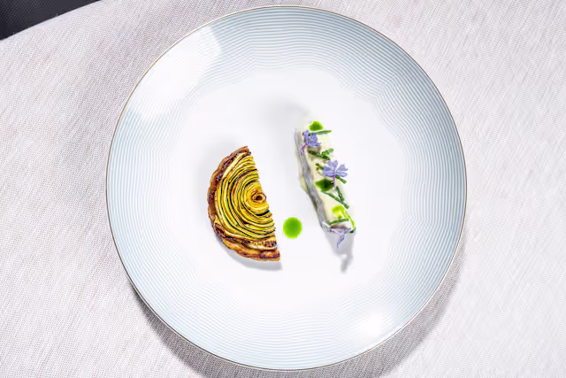 Torta di zucchine a spirale con ripieno cremoso, accompagnata da mousse leggera alle erbe e fiori edibili.
