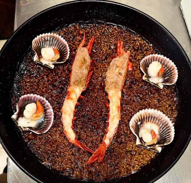 Paella marinera con Carabinero y zamburiñas. Arroz elaborado con un fondo sabroso de marisco y pescado, enriquecido con sepia y su coral, que aportan un intenso sabor a mar. El carabinero, grande y jugoso, es el protagonista absoluto