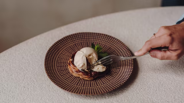 Base de masa hojaldrada con compota de frutas oscuras y helado de vainilla, decorada con menta fresca.