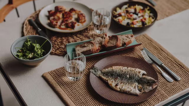 Pescado a la parrilla con hierbas frescas, acompañado de pollo asado, ensalada colorida y pan rústico.