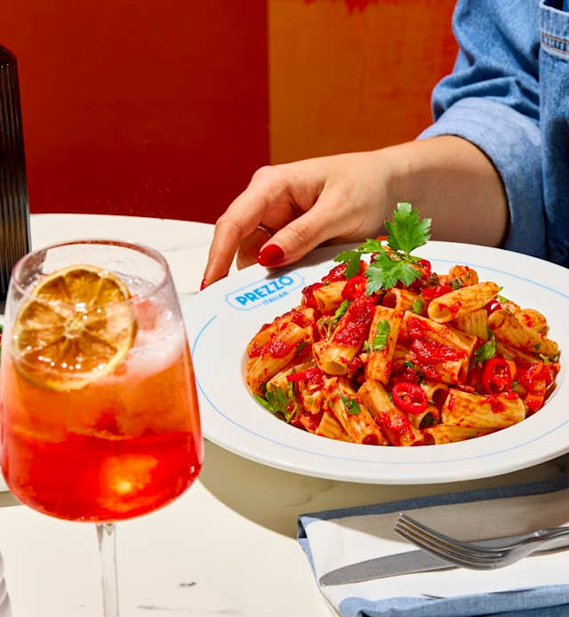 Rigatoni pasta in rich tomato sauce, garnished with fresh herbs and red chili slices, offering a vibrant and slightly spicy dish.