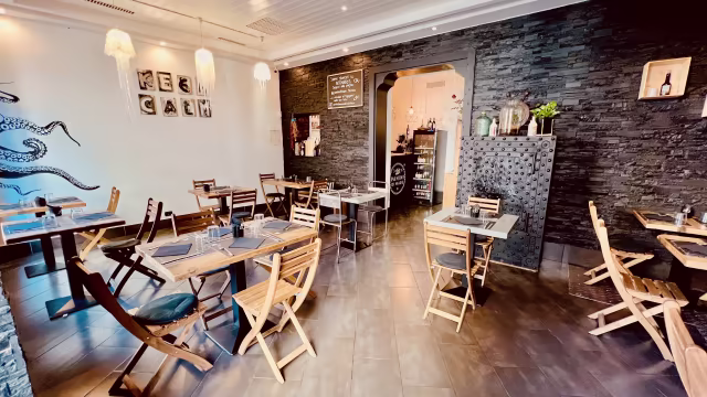 Interni del ristorante con design moderno e rustico, pareti in pietra scura e tavoli in legno eleganti, creando un'atmosfera accogliente.