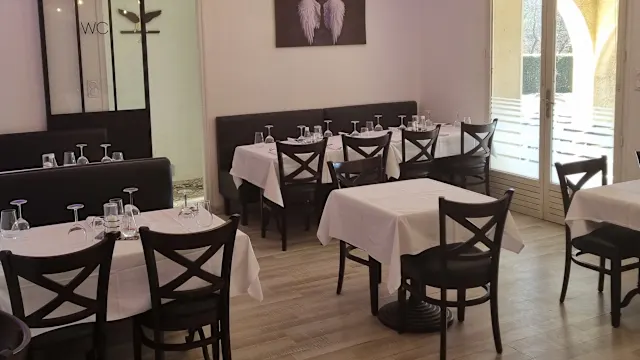 Intérieur de restaurant élégant avec des tables bien dressées, des chaises en bois foncé et des murs décorés de manière minimaliste, offrant une atmosphère accueillante.