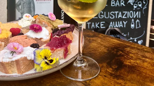 Assortimento di dolci colorati con torte e pasticcini decorati, accompagnati da un cocktail rinfrescante con lime e menta.