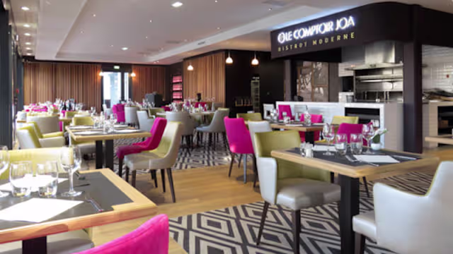 Intérieur moderne et stylé avec des sièges colorés, un éclairage naturel et doux, des accents en bois et une cuisine ouverte, créant une ambiance contemporaine et accueillante.