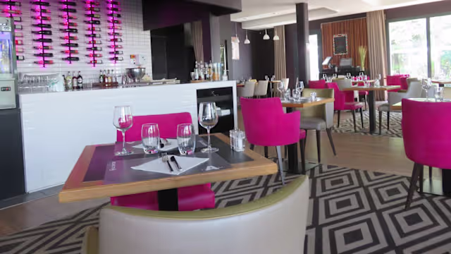 Intérieur moderne avec un mélange de couleurs et de textures, sièges en fauteuils moelleux, éclairage doux et grandes fenêtres créant une atmosphère accueillante.