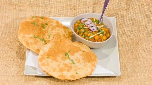 Puris doradas y crujientes acompañadas de chole, un curry de garbanzos especiado, con cebolla roja, yogur cremoso y hierbas frescas.